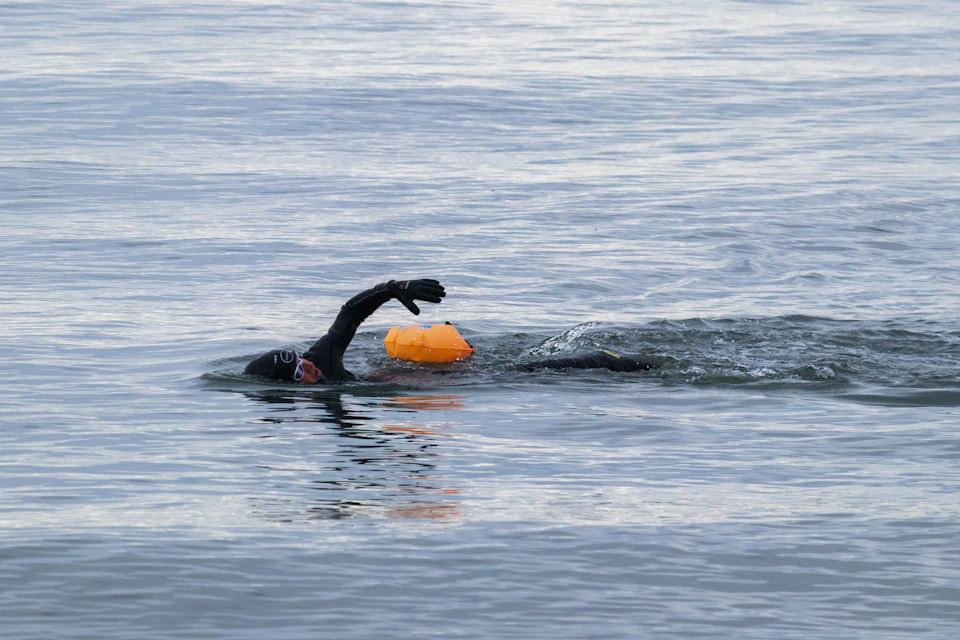 Nadador en el mar con una boya naranja de seguridad